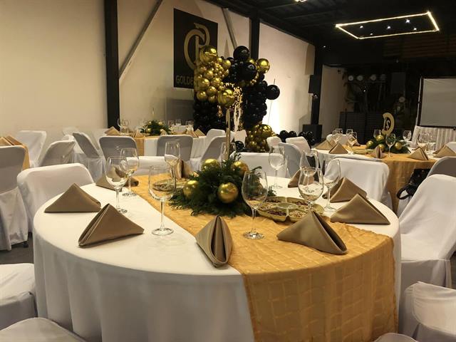 Mesa montada con mantel blanco y camino dorado