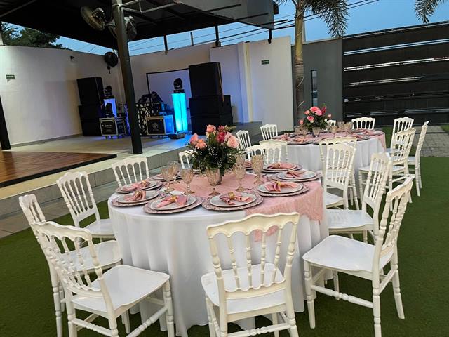 Mesa con mantel rosa y flores en el jardín